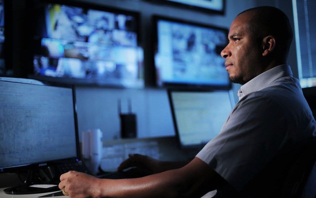 Profissional operando computadores em uma central de monitoramento e vigilância.