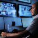 Profissional operando computadores em uma central de monitoramento e vigilância.