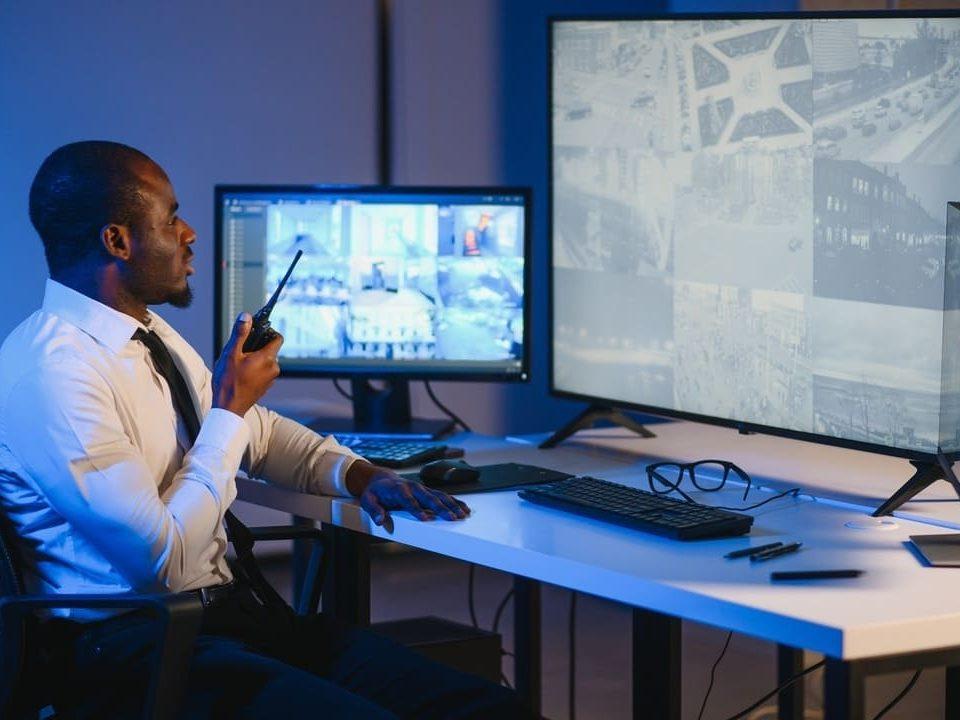 Segurança patrimonial monitorando câmeras de vigilância em sala de controle, garantindo a proteção de patrimônios e áreas restritas.