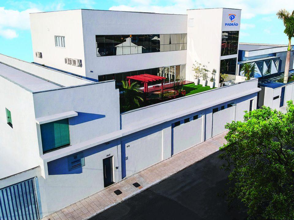 Fachada moderna de uma empresa de facilities, com estrutura limpa, área verde e logo da marca Padrão.