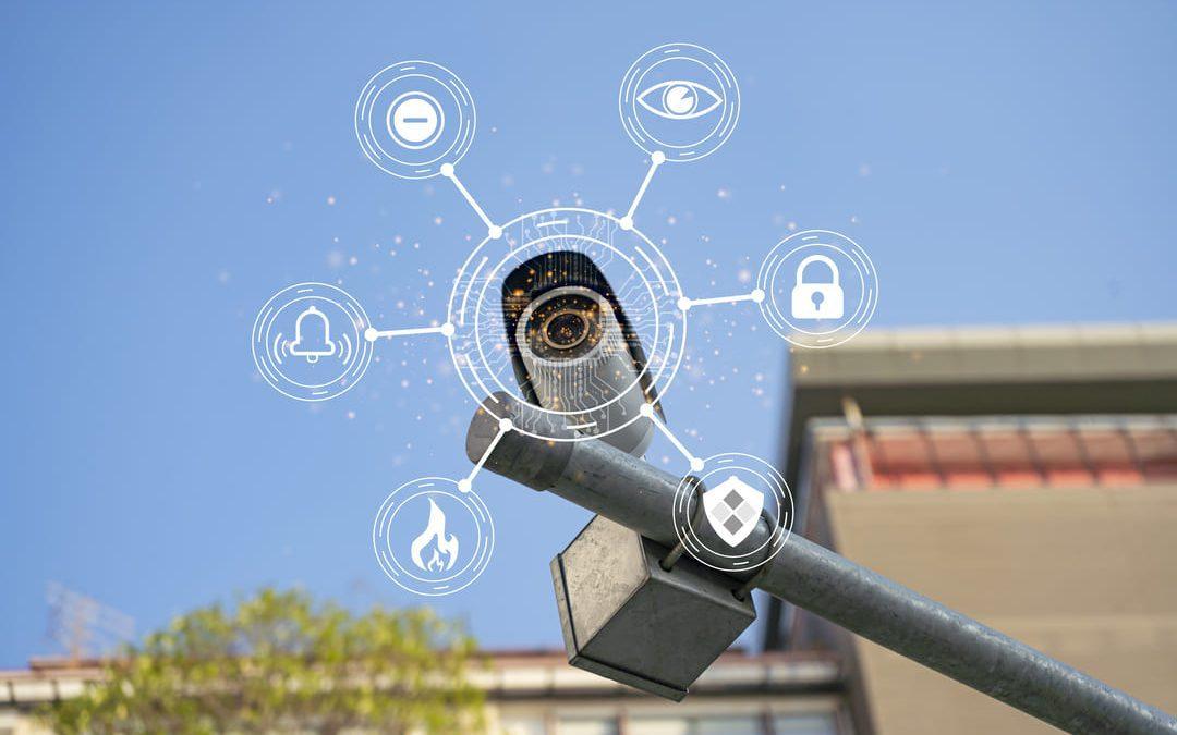 Câmera de segurança moderna com ícones digitais representando inteligência artificial e recursos de segurança, sobre fundo urbano e céu azul.