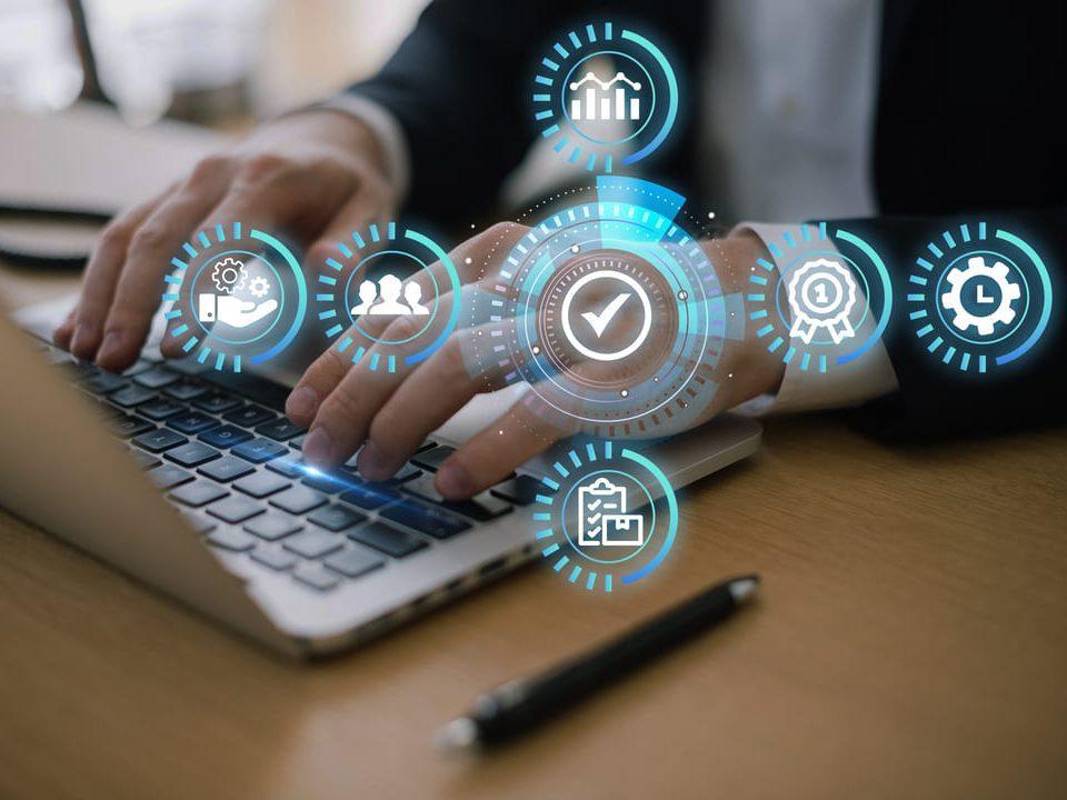 Pessoa digitando em notebook com ícones digitais representando processos de gestão integrada.