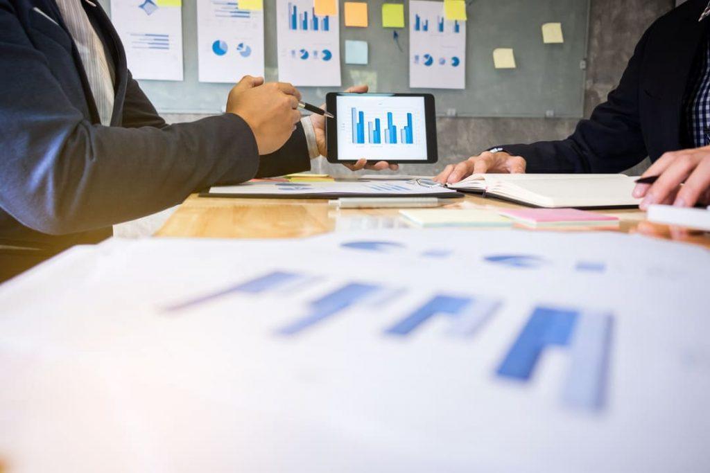 Profissionais analisando gráficos em uma reunião de planejamento de facilities.