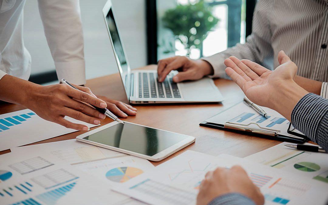 Equipe discutindo relatórios e dados durante o planejamento de facilities.