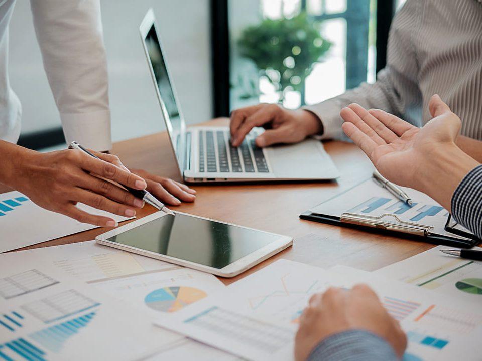 Equipe discutindo relatórios e dados durante o planejamento de facilities.