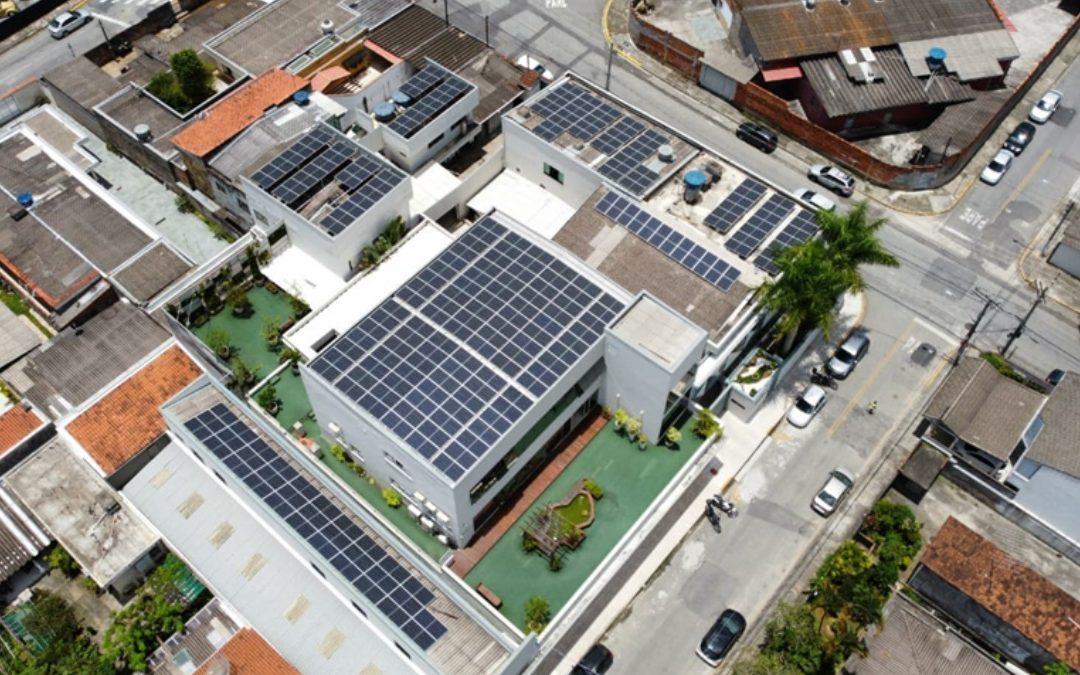 Vista aérea de edifícios com painéis solares instalados nos telhados em área urbana.