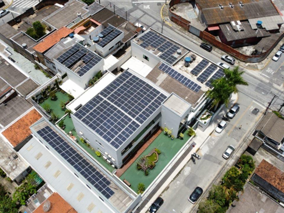 Vista aérea de edifícios com painéis solares instalados nos telhados em área urbana.