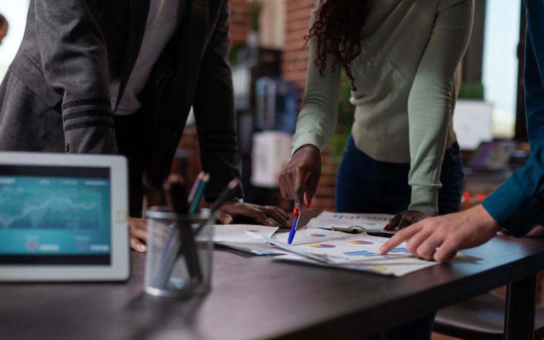 Equipe analisando gráficos e indicadores sobre uma mesa, representando planejamento operacional, análise de dados e alinhamento estratégico para resultados em 2026.