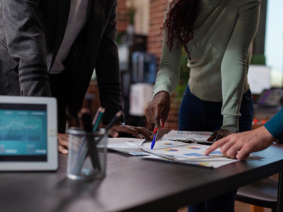 Equipe analisando gráficos e indicadores sobre uma mesa, representando planejamento operacional, análise de dados e alinhamento estratégico para resultados em 2026.