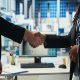 Dois profissionais apertando as mãos em ambiente corporativo industrial, simbolizando parceria estratégica e maturidade empresarial na gestão de serviços terceirizados.