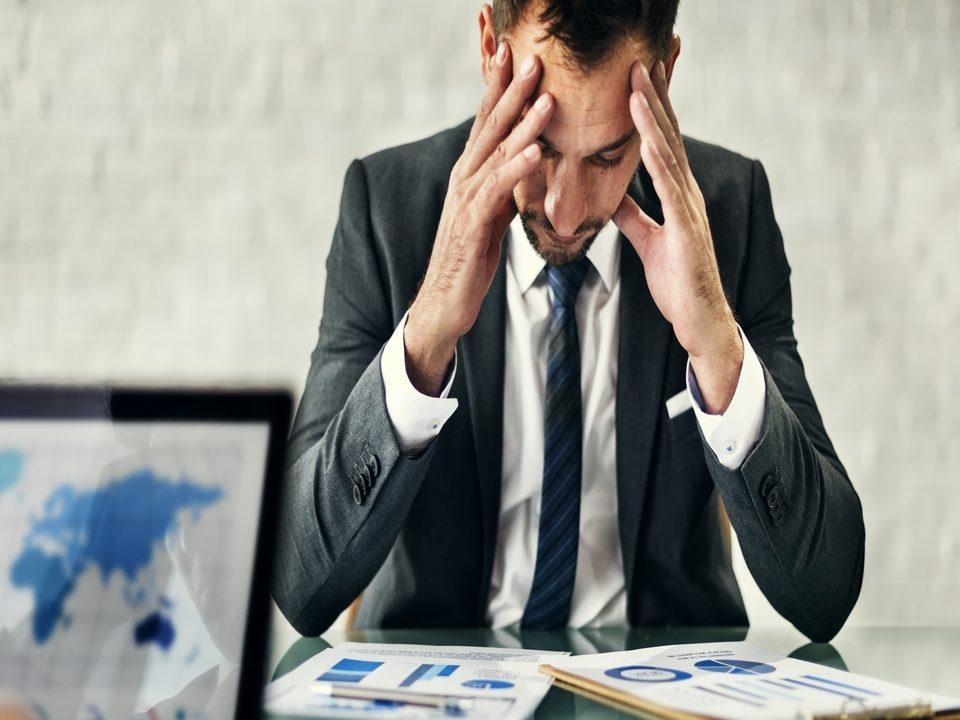 Gestor analisando relatórios com expressão de preocupação, ilustrando como a falta de planejamento pode aumentar o custo operacional e gerar pressão na gestão.