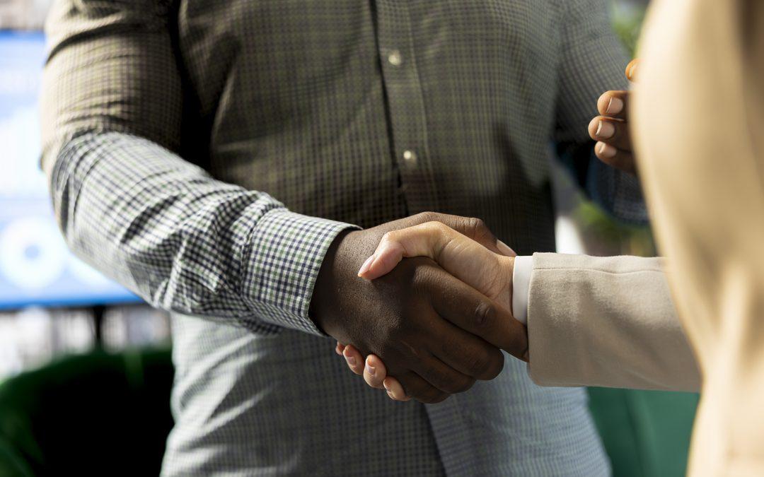 Duas pessoas apertando as mãos em ambiente corporativo, representando a troca de fornecedor como uma decisão estratégica para garantir continuidade, confiança e redução de riscos na operação.