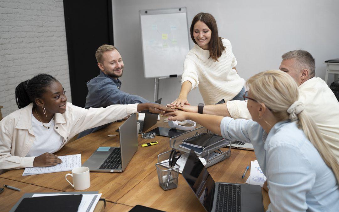 Equipe reunida em ambiente corporativo colocando as mãos juntas em sinal de colaboração, representando a importância das equipes operacionais na construção de operações eficientes e integradas.