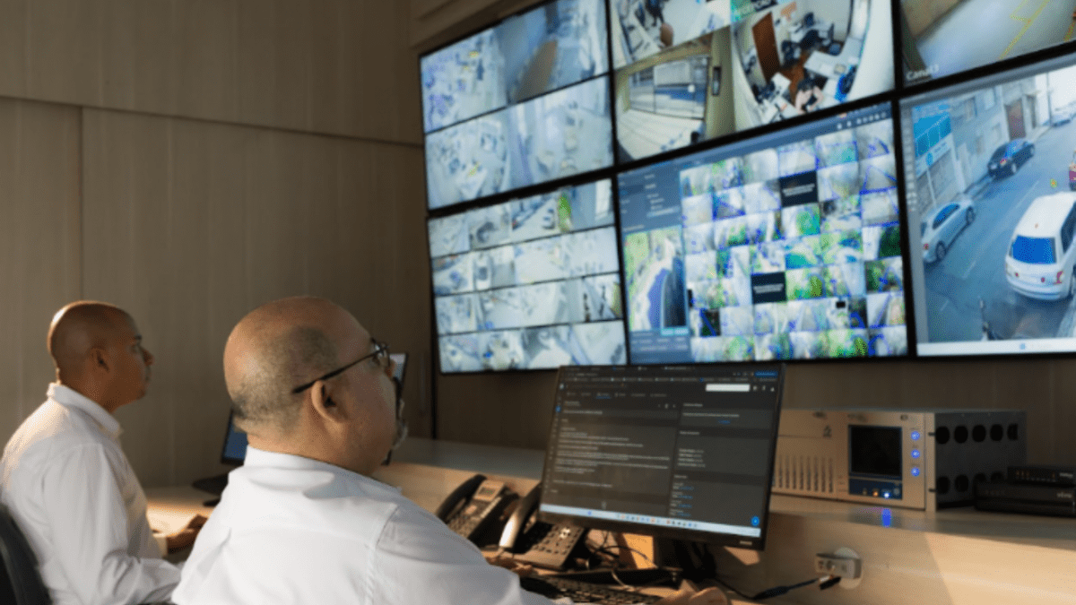 Central de monitoramento com operadores acompanhando imagens em tempo real por meio de múltiplas telas de segurança e vigilância.
