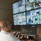 Central de monitoramento com operadores acompanhando imagens em tempo real por meio de múltiplas telas de segurança e vigilância.