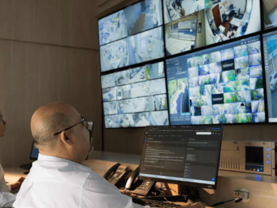 Central de monitoramento com operadores acompanhando imagens em tempo real por meio de múltiplas telas de segurança e vigilância.