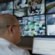 Profissional monitora câmeras de segurança em uma central de controle, atividade relacionada à gestão de facilities.